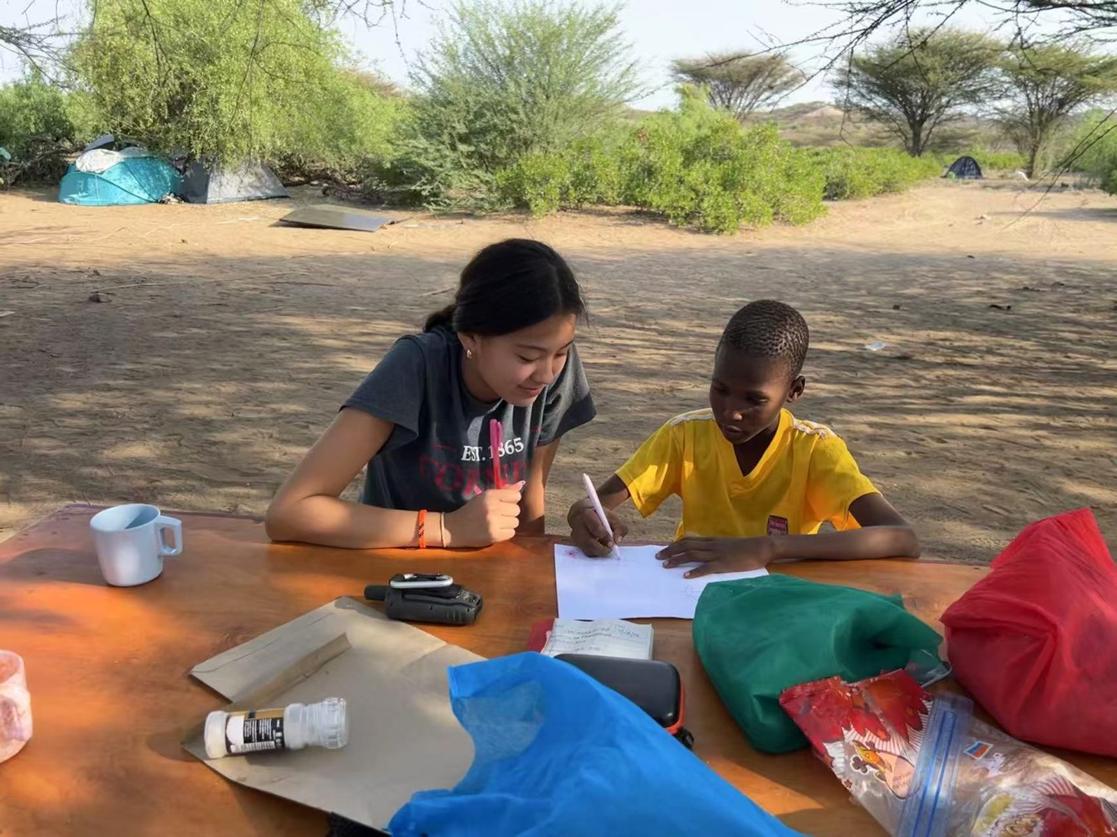 Joy tutoring a student at an outdoor table in Turkana, Kenya