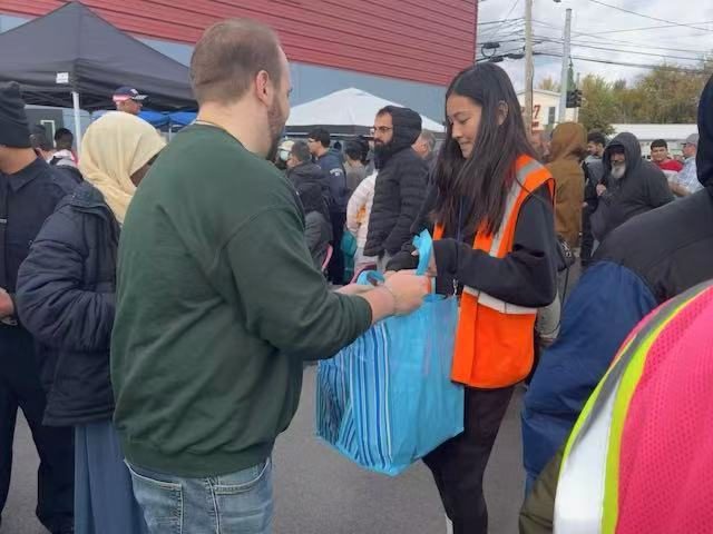 Joy handing a grocery bag to a visitor at the pantry